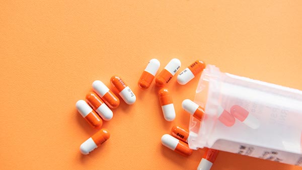 Orange and white pills spilling out of a bottle